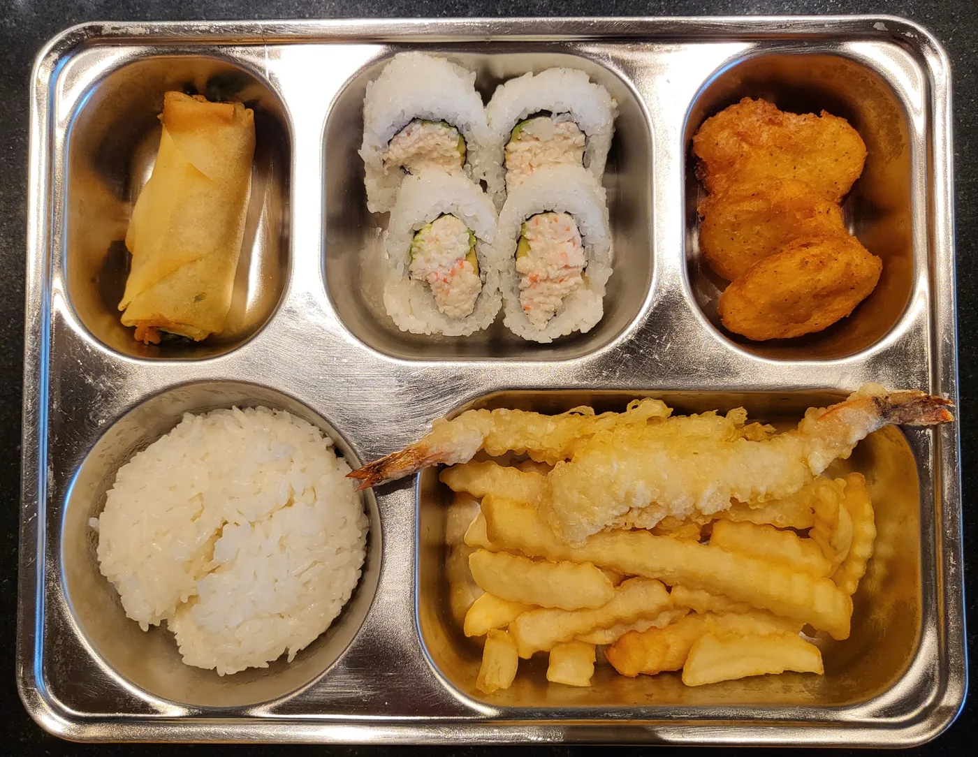 A kids meal tray with a roll, rice, fried pieces and an egg roll
