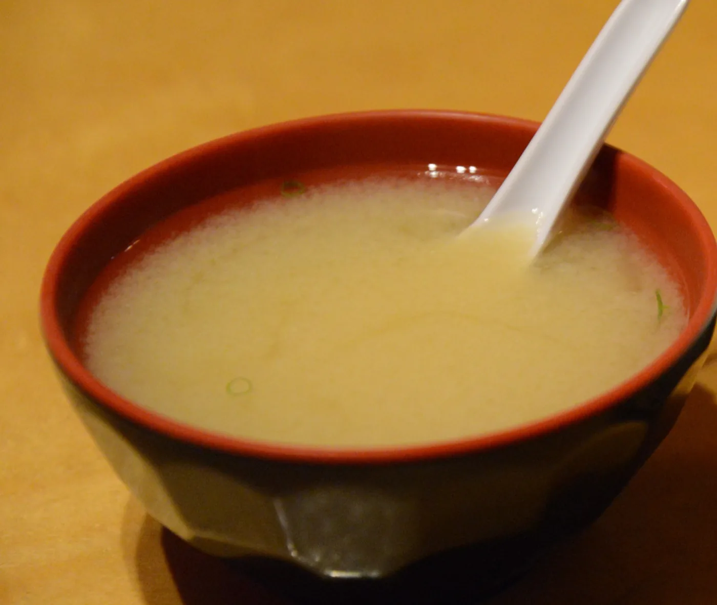 Miso Soup in a dark red lacquer bowl with a spoon