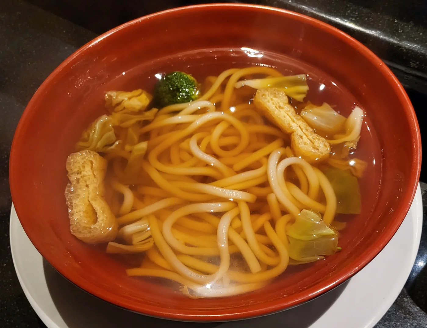 Plain Udon with seaweed, fish cake and fried tofu in a dark bowl