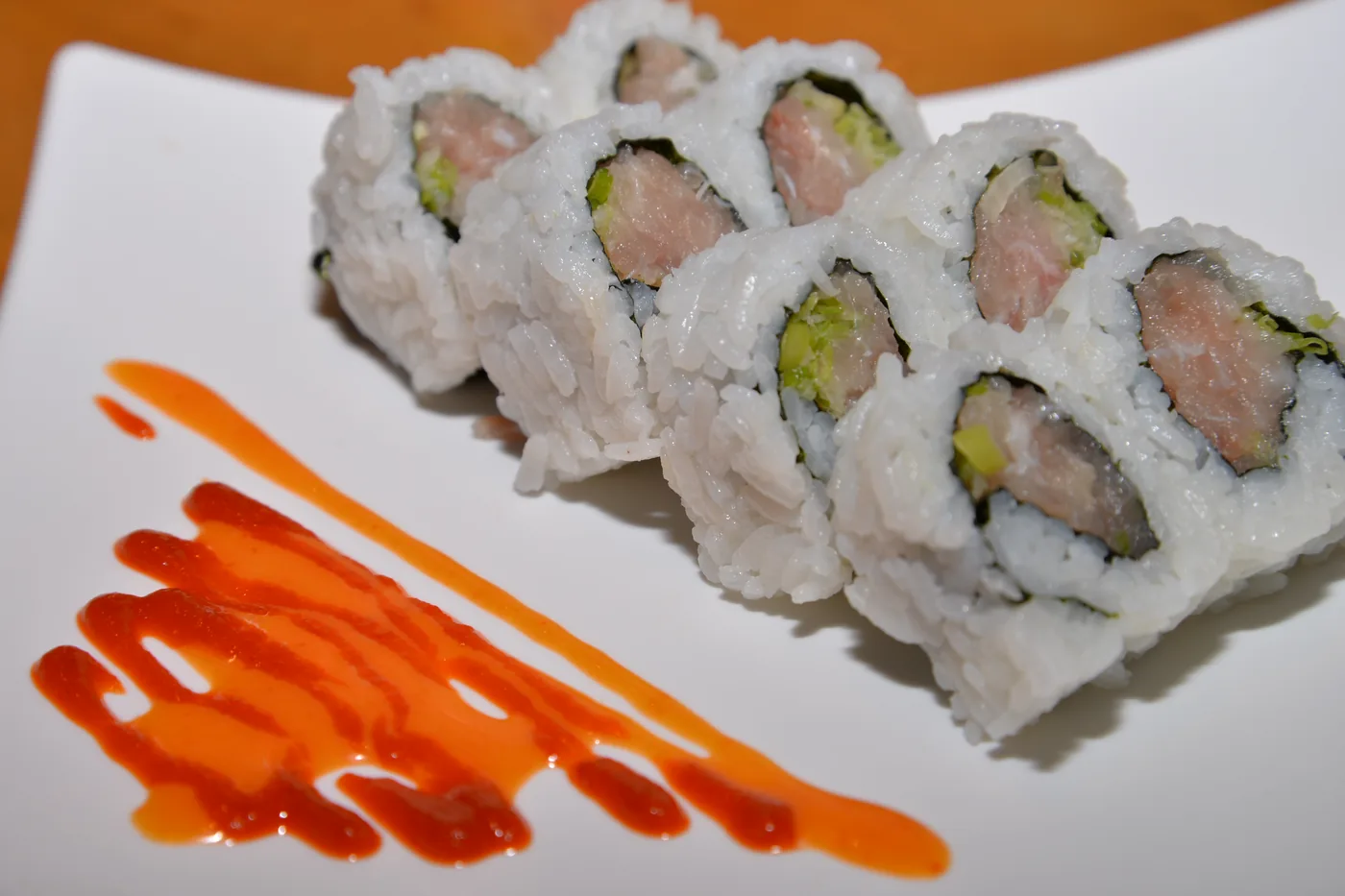 Spicy Yellowtail Roll cut into pieces on a white plate