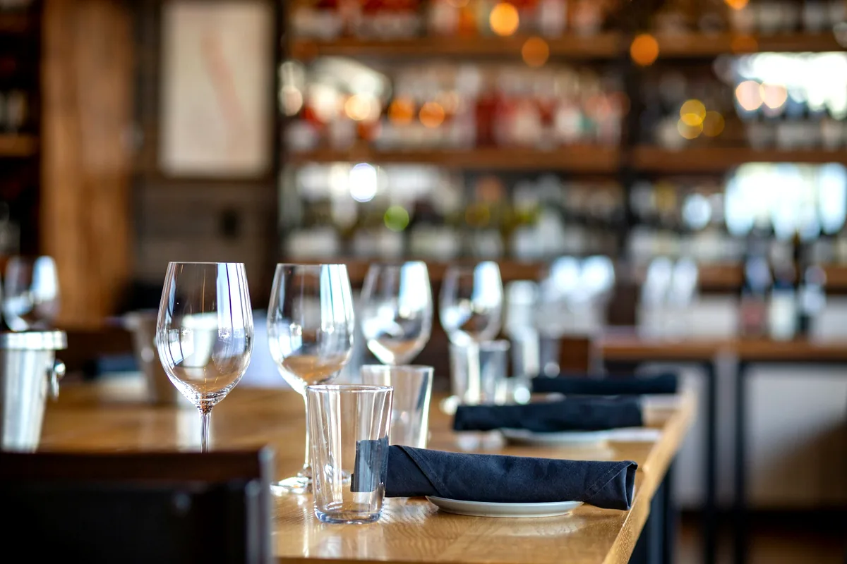 Warmly lit restaurant tables laid with glassware before service