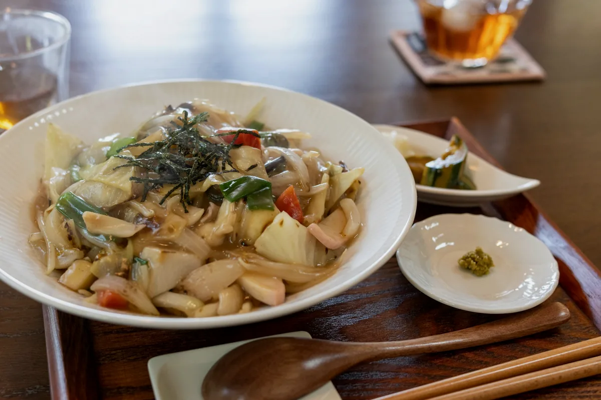 A bowl of thick stir-fried noodles tossed with cabbage and mixed vegetables